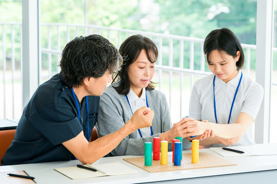 Doctor and female nurse learning rehabilitation techniques using training materials for hand function and occupational therapy practice