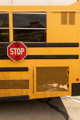 Yellow School Bus Side with Red Stop Sign. Close-up side view of a yellow school bus featuring a red octagonal stop sign, reflective windows, black protective strips. © Ian