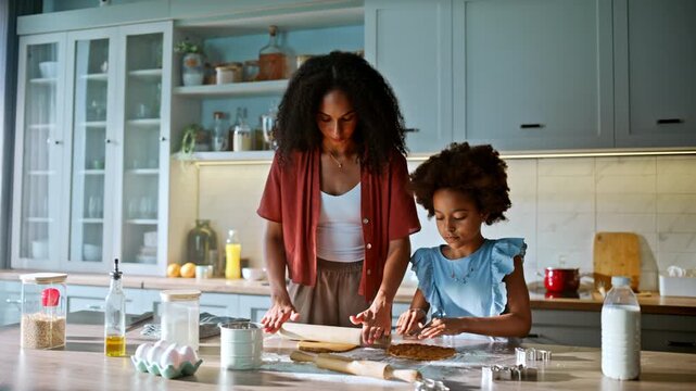 Young mom rolling dough girl kitchen. Multiethnic family baking cookies home.