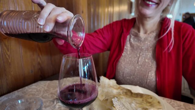 With a glass of wine woman indulges in rich flavors of a Borlengo: traditional dish from Emilia-Romagna, Italy, beloved in the of Modena and Bologna provinces. A delightful medley of meat and cheese