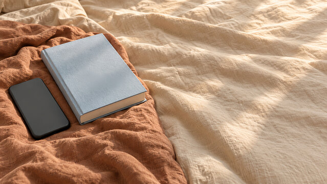 Closed book and smartphone on linen bedding for digital detox