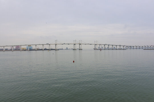 Cross-sea bridge fading into thick fog over calm water in Macao China
