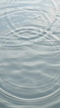 Concentric water ripples expanding on a calm grey lake surface in minimalist natural light