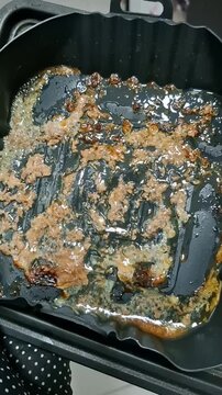 Rendered fat dripping from cooked meat into air fryer tray, close up of cooking process and homemade food preparation