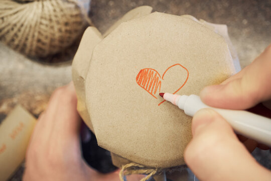 Hand drawing red heart symbol on brown craft paper wrapping homemade gift