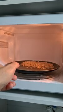 Person removing freshly heated rice from microwave, steaming hot homemade meal and everyday kitchen food preparation