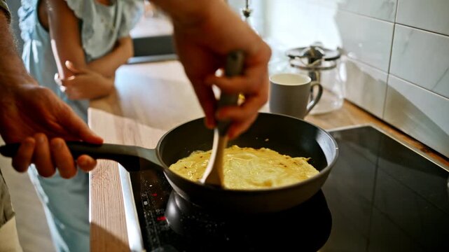 Closeup male hands folding omelette frying pan. Home breakfast cooking kitchen.