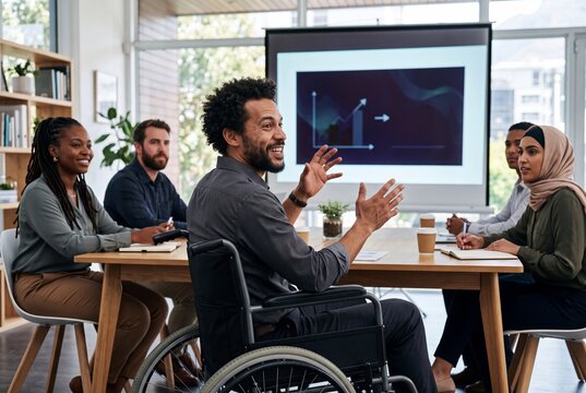 Diverse Team Collaboration: A man in a wheelchair leads a dynamic meeting, gesturing enthusiastically as his diverse colleagues attentively listen.
