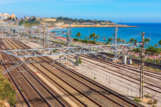 Coastal railway tracks in Tarragona run directly parallel to sandy beach and Mediterranean Sea. Captured from an elevated viewpoint, this sunny scene highlights Spain scenic transportation networks.