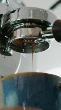 4K Pouring coffee stream from professional machine in cup. Barista man making double espresso, using filter holder. Flowing fresh ground coffee. Drinking roasted black coffee in the morning.	