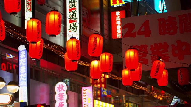 Glowing red Japanese paper lanterns hanging above a neon-lit urban street at night, traditional signage and string lights in background