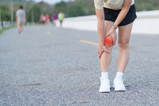 Young adult female runner with knee pain from ACL injury or patellofemoral syndrome. woman having joint ache, ligament tear or patellar tendinitis during running. Sports medical and healthcare concept