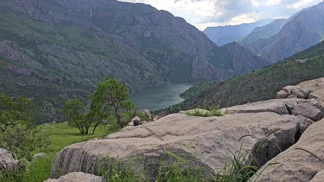 Calm lake in a steep mountain valley, with large boulders and grass swaying in the gentle wind and tree leaves rustling under a cloudy sky.
📍 Hawraman, Sarvabad, Kurdistan 