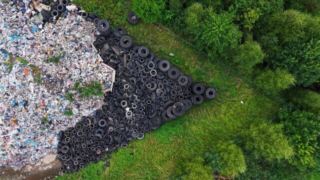 Top-down shot contrasts black rubber waste with woodland at a Latvian landfill.