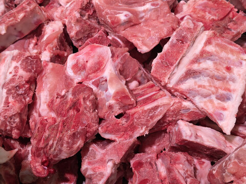 Raw pig bone meat close up with red muscle, white fat, and exposed bone texture for food preparation