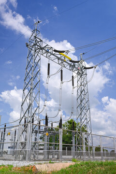 High voltage substation with steel transmission tower, power line, and blue sky