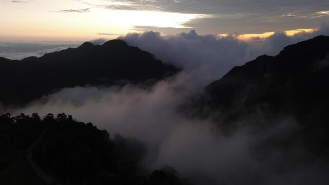 Misty Mountain Ridge at Dusk with Rolling Cloud, Forested Valley, Layered Peak Landscape, Glowing Sunset Horizon, Dramatic Highland Scenery, Tropical Slopes and Atmospheric Alpine View