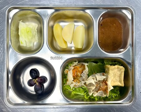 Healthy school meal with dumplings grapes apple and vegetables