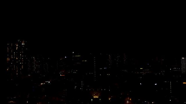 Nighttime city skyline with sudden lightning strike illuminating the dark sky and urban buildings