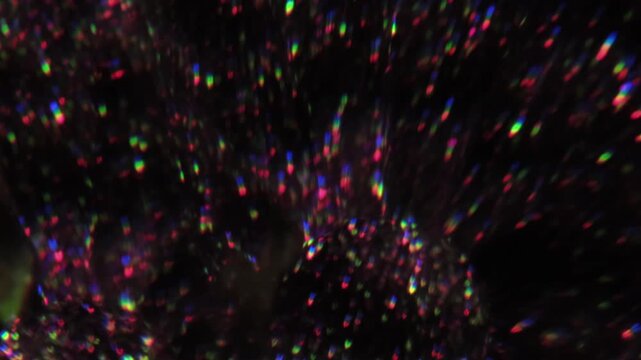 Blur crystal glare. Neon light background. Defocused purple green yellow color lens flare leaking on illuminated glitter creative optical dark black art abstraction.