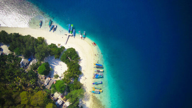 Drone aerial view of tropical island beach peninsula with turquoise sea gradient and wooden boats