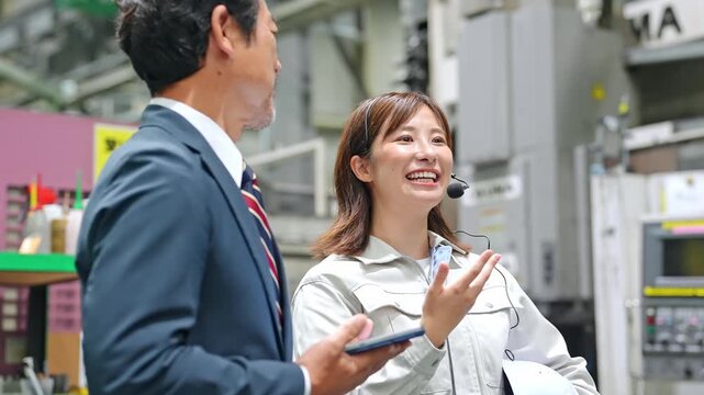 A male businessperson and a female factory worker inspecting a factory.