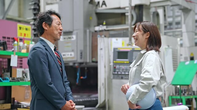 工場で会話する男性ビジネスパーソンと女性作業員