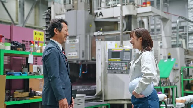 工場の中で握手する男性ビジネスパーソンと女性作業員