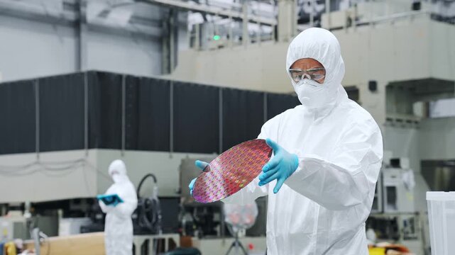 工場で機械を操作する防塵服を着た男性作業員