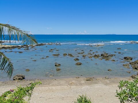 Scenic tropical beach with rocky tide pools and Guishan Island on the horizon in Hualien, Taiwan.