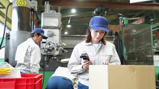 工場でハンディターミナルを使って製品を検査する女性作業員