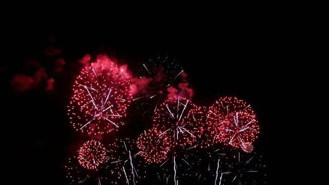 Red and gold fireworks exploding in the dark night sky during a celebration.