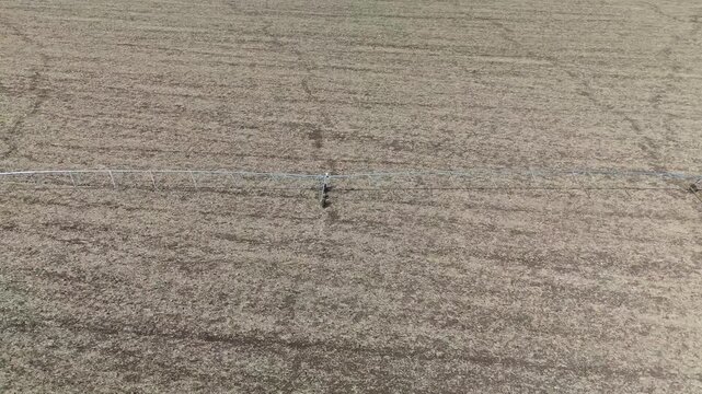 Aerial view of a center-pivot irrigation system spanning a dry agricultural field near Debrecen, Hungary, highlighting summer water management in a rural landscape.