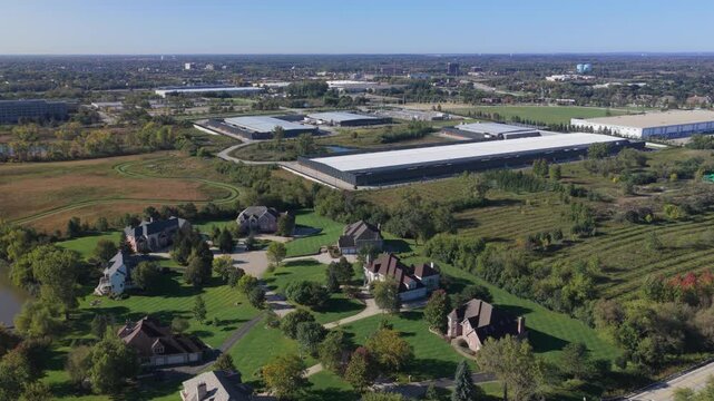 Aerial view of a large industrial data center surrounded by residential houses, green lawns, and trees