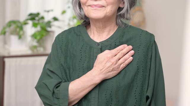 胸に手を当てる高齢の日本人女性、心臓、心疾患、不整脈、ペースメーカー、循環器系の医療を表現するシニアの顔なしイメージの動画
