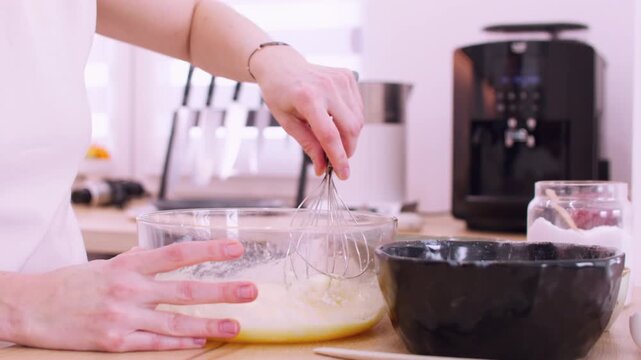 Pastry cooking. Mixing meal. Female chef hand stirring batter dough with whisk at light home kitchen workplace preparing tasty dessert.