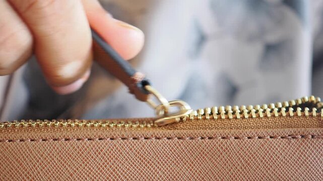 Close-up of a hand zipping a bag in a casual setting