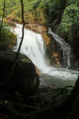 A serene waterfall cascading over rocks, surrounded by lush green foliage. © k33pcalmncapture