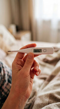 Person holding digital thermometer showing elevated temperature fever symptom medical care concept