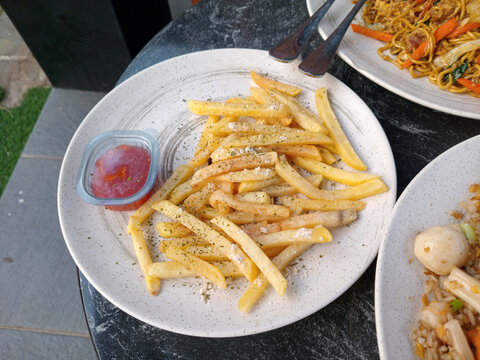 Crispy french fries seasoned with herbs served with tomato chili sauce