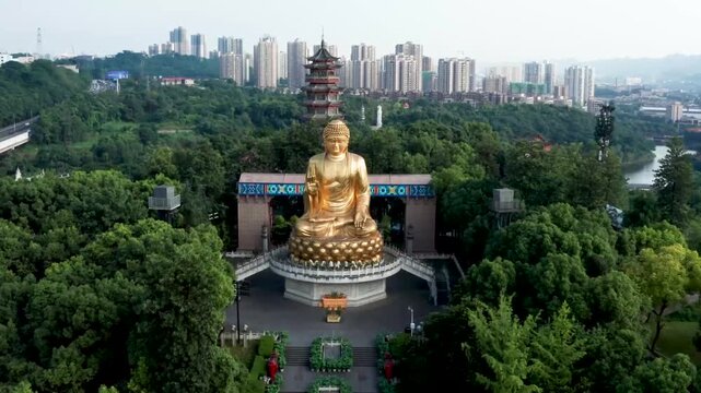 Aerial drone footage of a massive golden Buddha statue seated in meditation before a traditional Chinese temple complex, with a multi-tiered pagoda and modern city skyline in the background