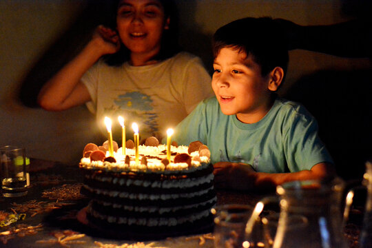 Smiling boy and birthday cake in the darkness.