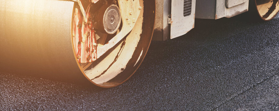 Industrial Road Roller Presses Fresh Dark Asphalt on a City Street During Daytime Work