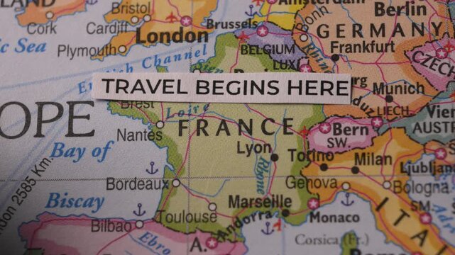 Travel Begins Here Paper Strip Placed on Map of Europe