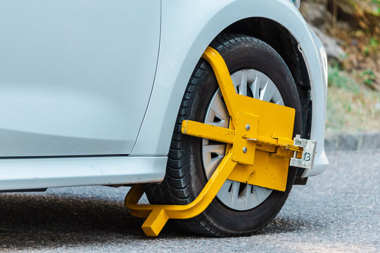 Close-Up of Yellow Wheel Clamp Securing Parked Car Tire