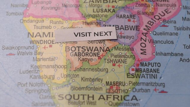 Person placing Visit Next note on map of Southern Africa travel planning