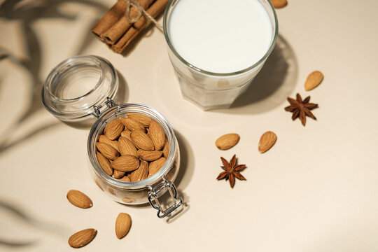 Almonds in a jar with a glass of almond milk and cinnamon sticks