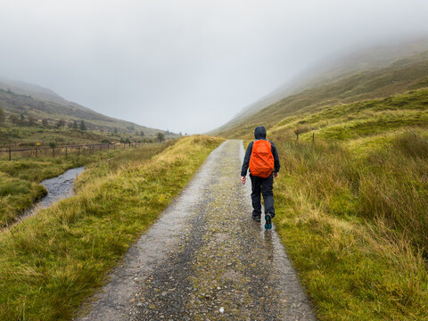 A hiker walking along a very wet West Highland Way trail in the rain on the moors between Tyndrum and Auch in Scotland
