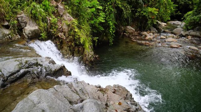 Tropical Waterfall Flowing Into Crystal Clear River in Rocky Forest 4K
