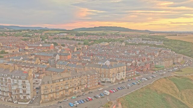 Saltburn-by-the-Sea rises inland from Marine Parade, with Victorian terraces, Valley Gardens and the Cleveland Hills visible beyond the town, Redcar and Cleveland, England, drone ascent.
